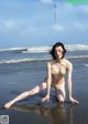 A woman in a bikini sitting on the beach.